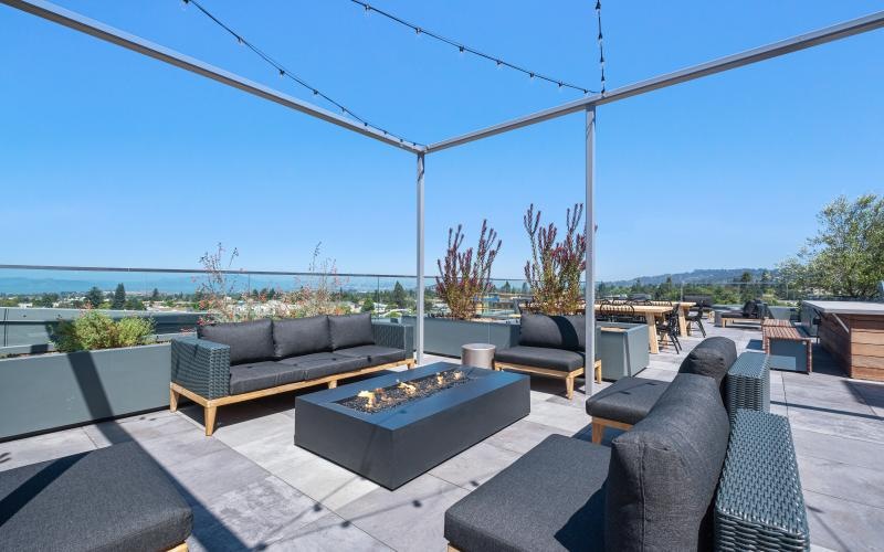 a patio with a fire pit and chairs and a view of the ocean