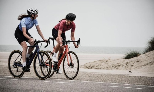 A beautiful community at the heart of all your passions women bicycling on the road along a beach